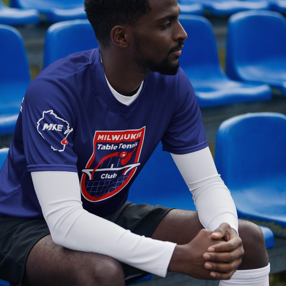 Player in the bleachers wearing the new blue Milwaukee Table Tennis Club jersey